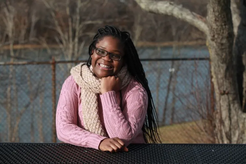 Senior portrait of a smiling young woman by the water on a winter afternoon