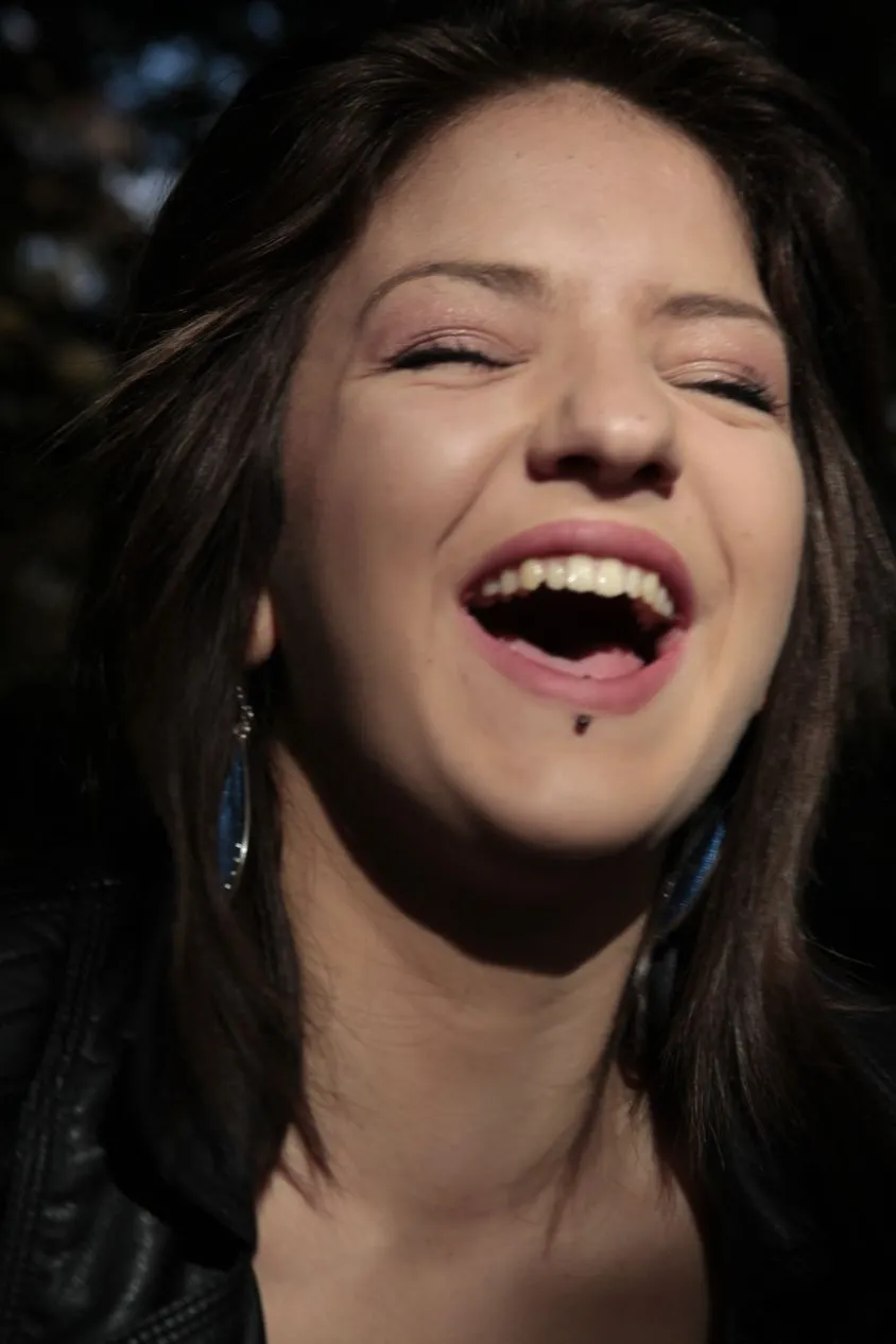 Close portrait of a young woman laughing in natural light