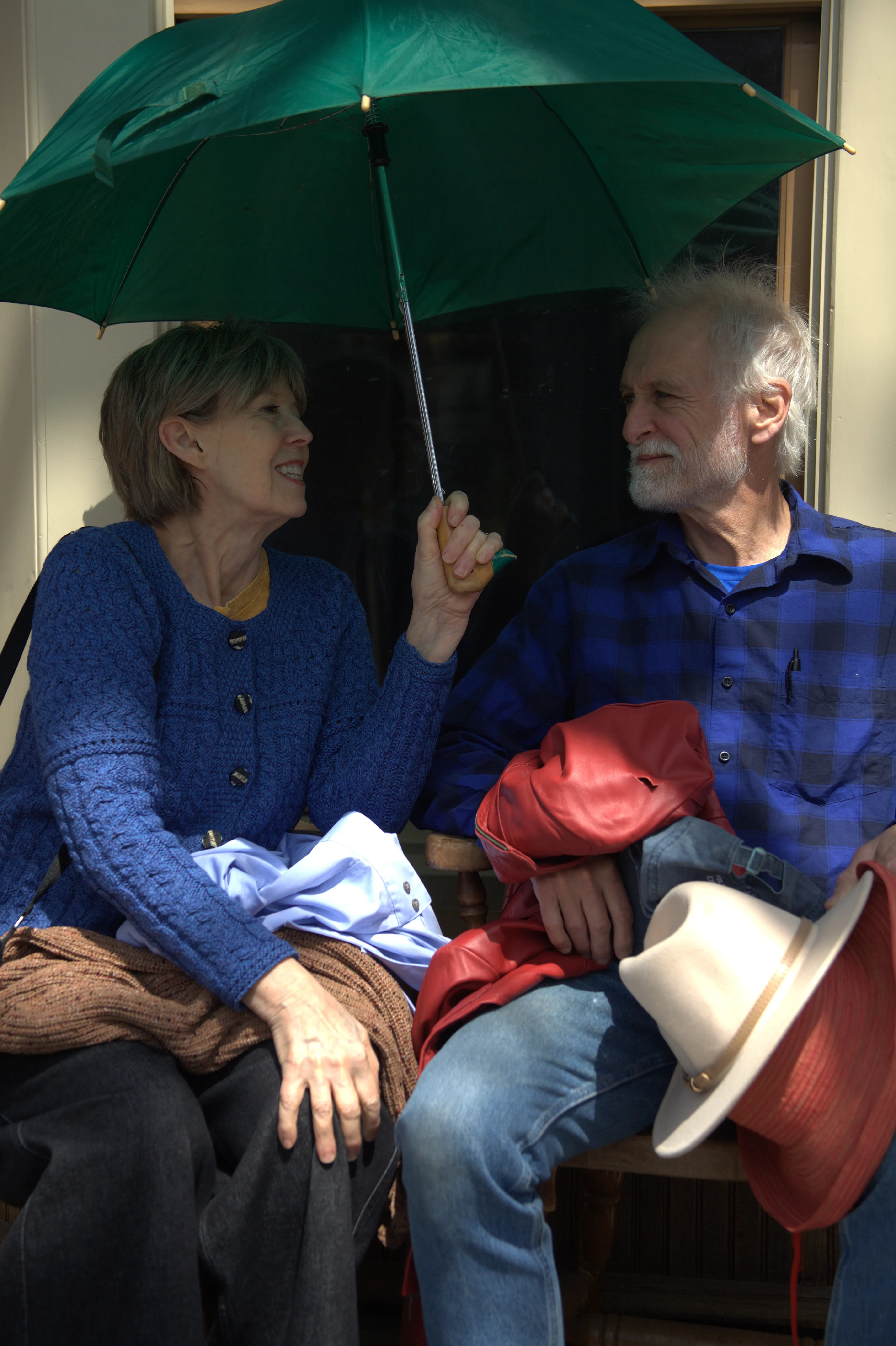 Older couple sitting together beneath an umbrella